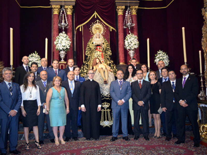 Grupo de personas posando frente a una imagen religiosa en un ambiente ceremonial.