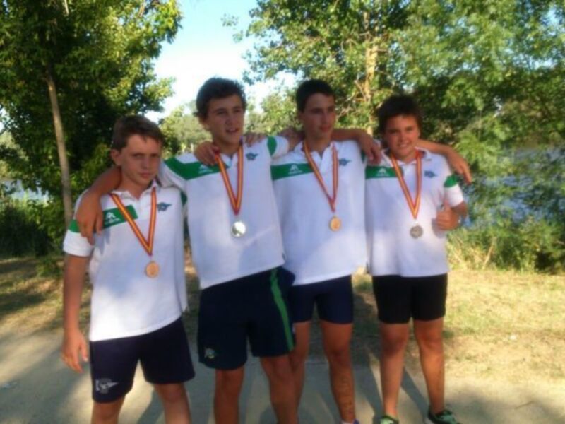 Equipo juvenil con medallas posando juntos al aire libre.