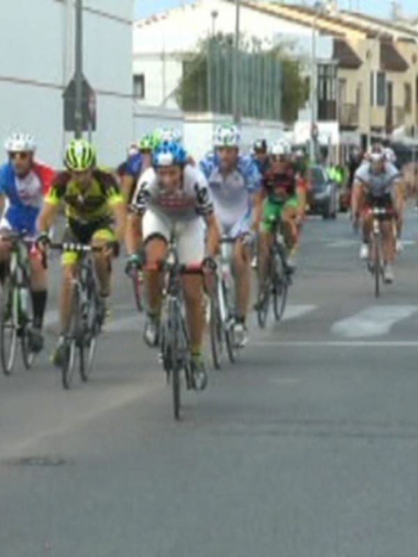 Corredores en una carrera de ciclismo, con el público animando desde los lados.