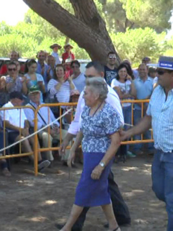 Un hombre y una mujer caminan juntos mientras una multitud observa en un evento al aire libre.