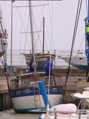 Barcos amarrados en un puerto con una persona trabajando cerca de uno.