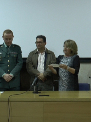 Conferencia o presentación en un salón de reuniones con un panel de personas, incluyendo uniformados y civiles, en un ambiente formal.