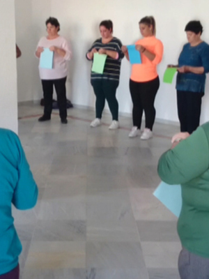 Una clase de yoga en una sala de aula con mujeres en diferentes posiciones de yoga, sosteniendo tarjetas de colores.