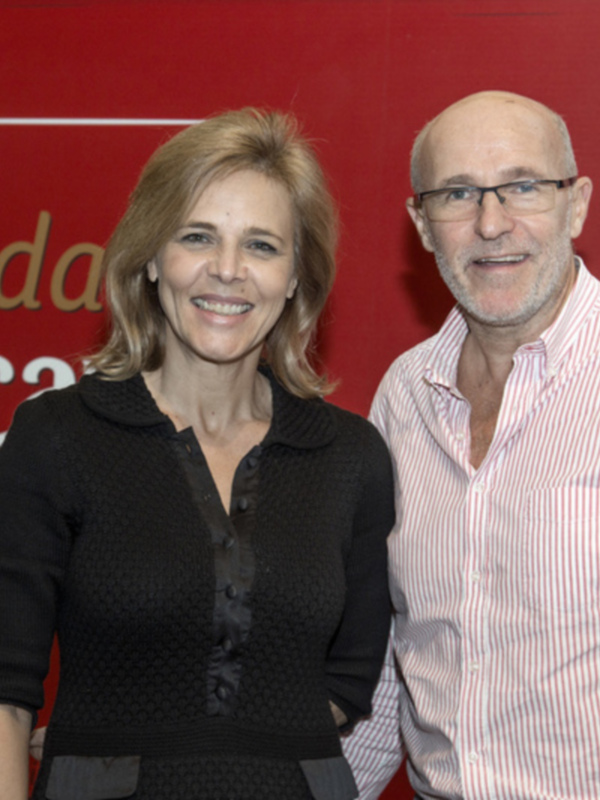 Dos personas sonrientes posando frente a un fondo rojo con el logotipo de la Fundación Cruzcampo.