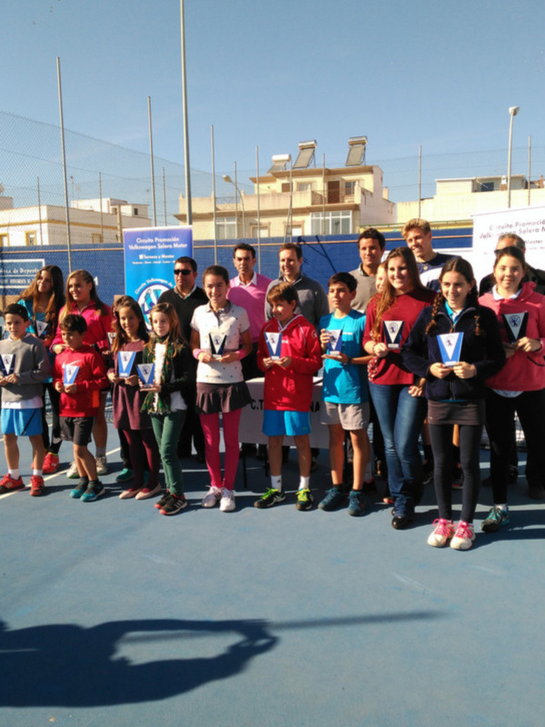 Ganadores de un torneo de tenis celebran con sus trofeos en un campo de tenis.