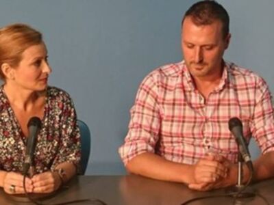 Dos personas sentadas frente a micrófonos, posiblemente en una conferencia o entrevista.