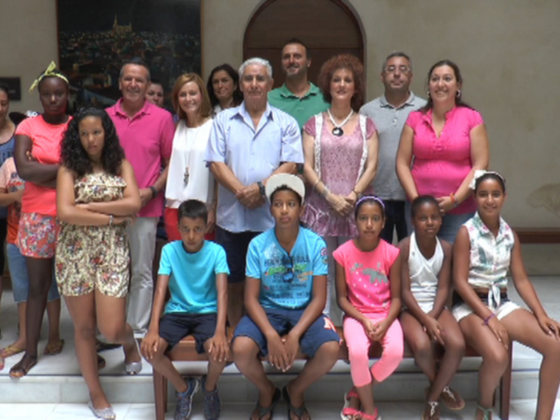 Una familia y amigos posan juntos en una foto formal, con un fondo que incluye elementos decorativos y una puerta. La imagen transmite una sensación de unidad y felicidad familiar.