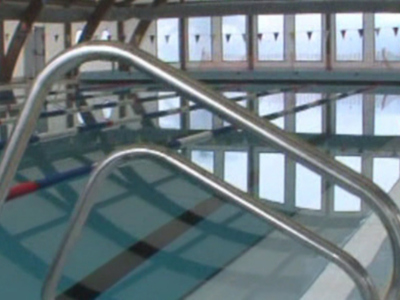 Piscina interior con líneas de natación y barandillas metálicas.