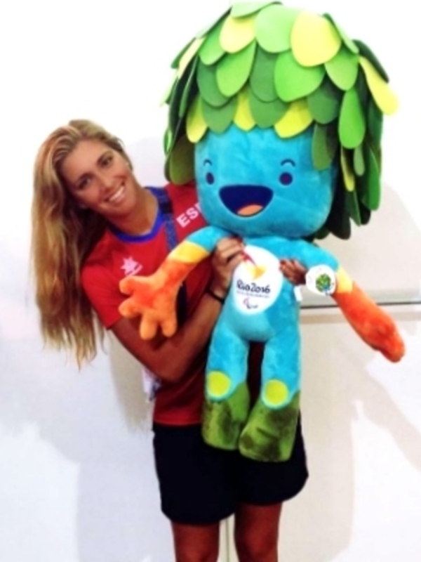 Una mujer sostiene a la mascota oficial de los Juegos Paralímpicos de Río 2016, que es un personaje con una piel azul y verde con detalles en amarillo y naranja.