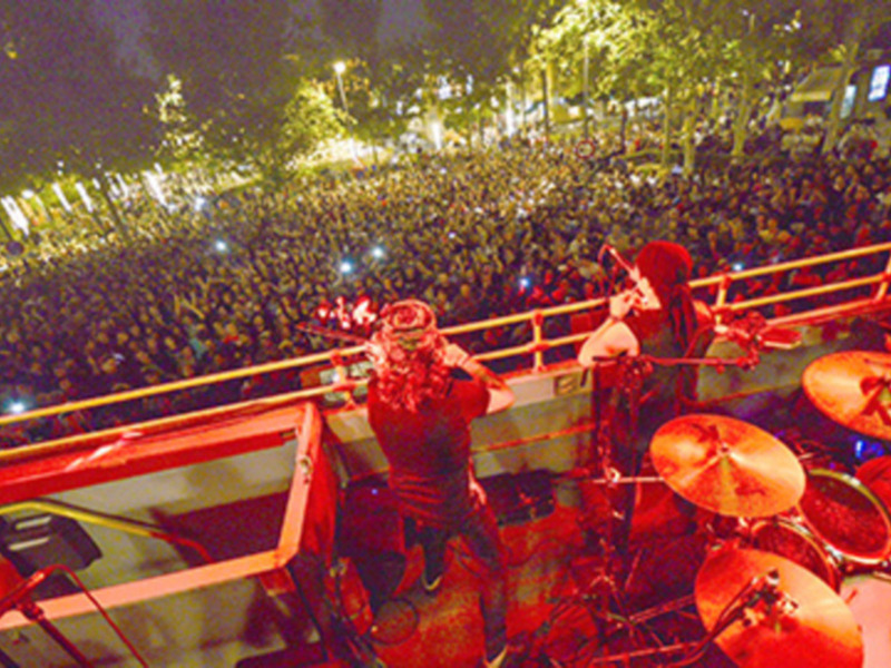 Un músico en un escenario con un gran público en la noche, tocando un instrumento de percusión.