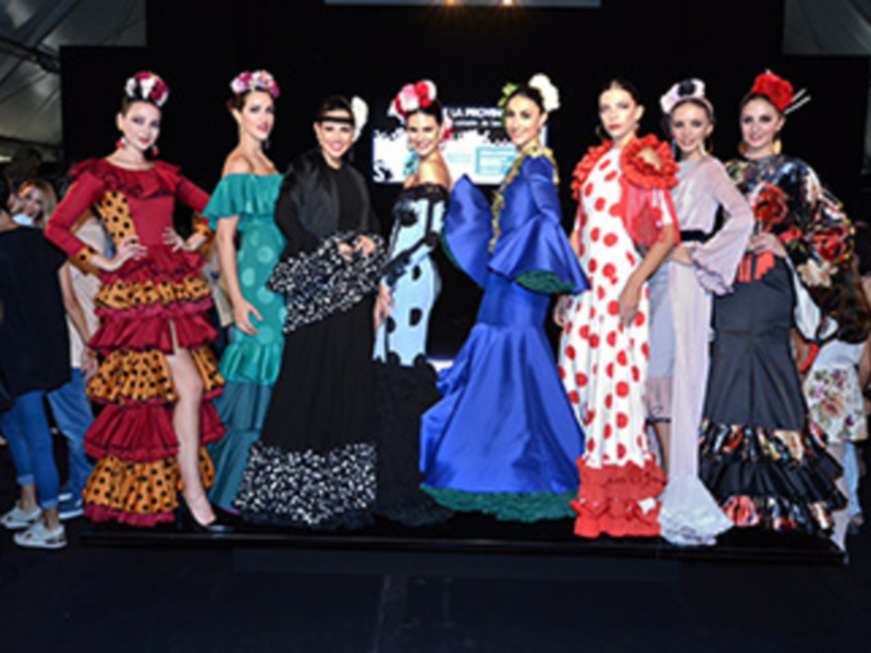 Modelos posan con trajes de flamenca coloridos y originales en un desfile.