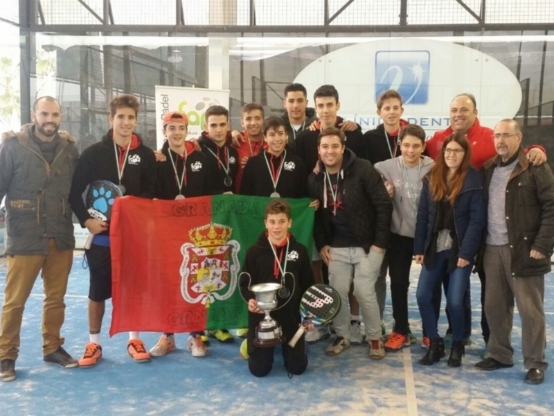 Equipo de padel celebrano un triunfo en un torneo de padel en Granada, con medallas y una bandera de la ciudad.
