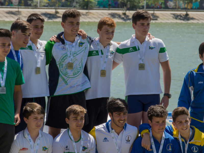 Equipo de jóvenes nadadores posando en la orilla del río, con medallas y uniformes deportivos.