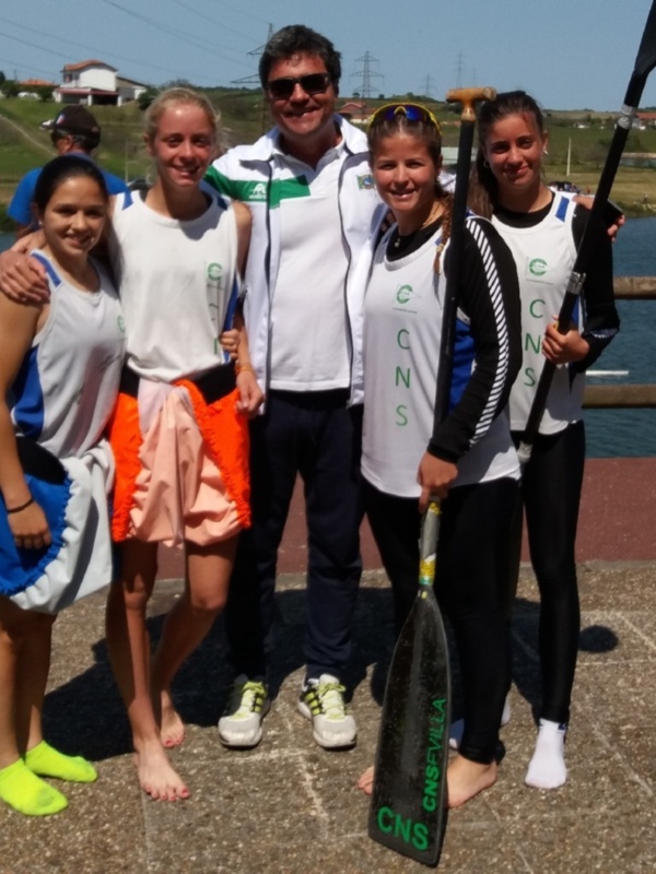 Un grupo de personas posando junto a un río, con una persona sosteniendo una paleta de remo.