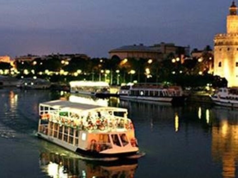 Puerto de Sevilla en la noche, con el Torre del Oro y varios barcos.