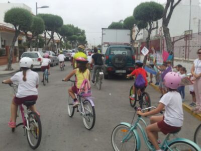 Niños en bicicleta con cascos, participando en una actividad ciclista bajo un cielo nublado.