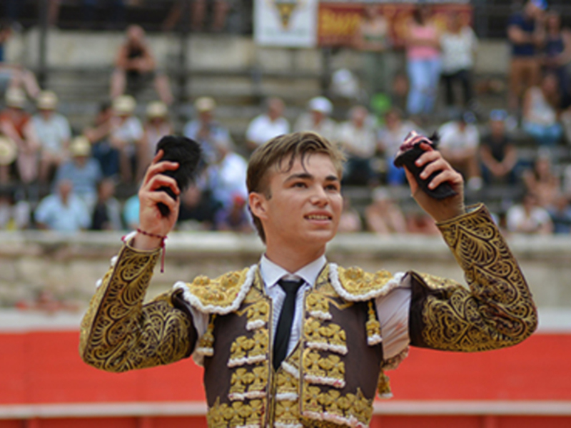 Joven torero en traje de luces, celebrando en el ruedo durante una corrida de toros.
