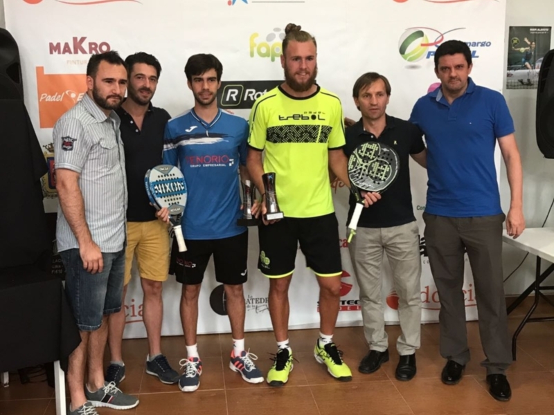 Equipo de padel posando con trofeo en un evento deportivo.
