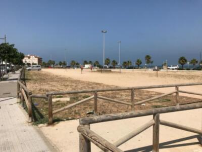 Playa con arena y madera, cerca de edificios y árboles.