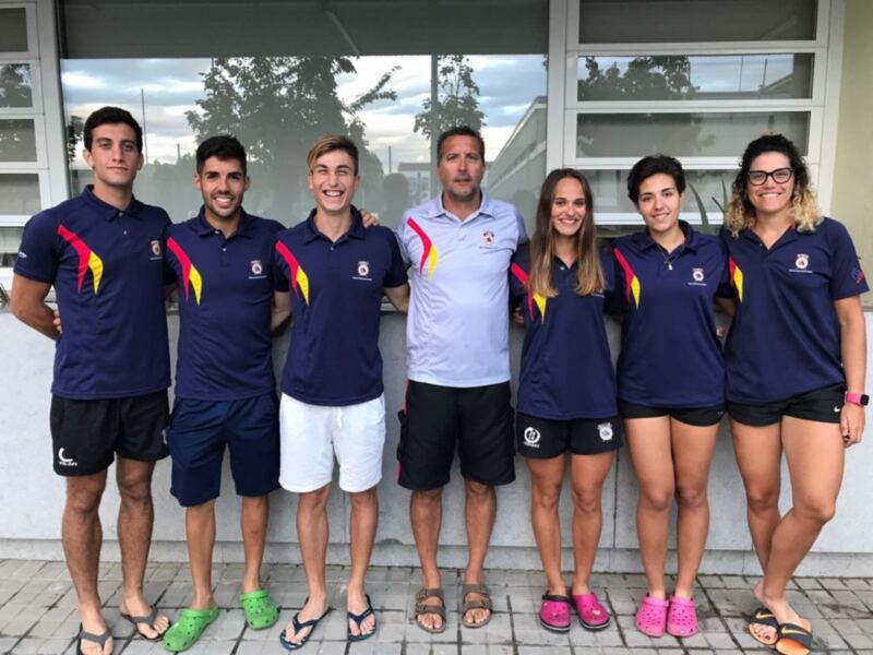Equipo deportivo posando juntos en una fila, vestidos con uniformes de color azul y detalles rojo y amarillo, sonrientes y listos para competir.