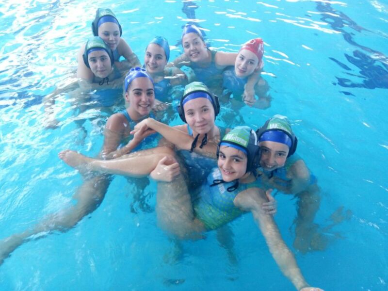 Equipo de natación en una piscina, disfrutando y sonriendo juntos.