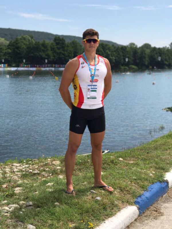 Triatleta en traje de competición posando junto al lago.