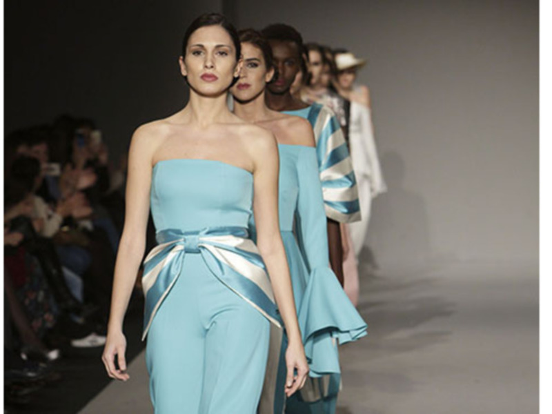 Modelos desfilando en la pasarela de una moda de alta costura, con vestidos azules y accesorios elegantes.