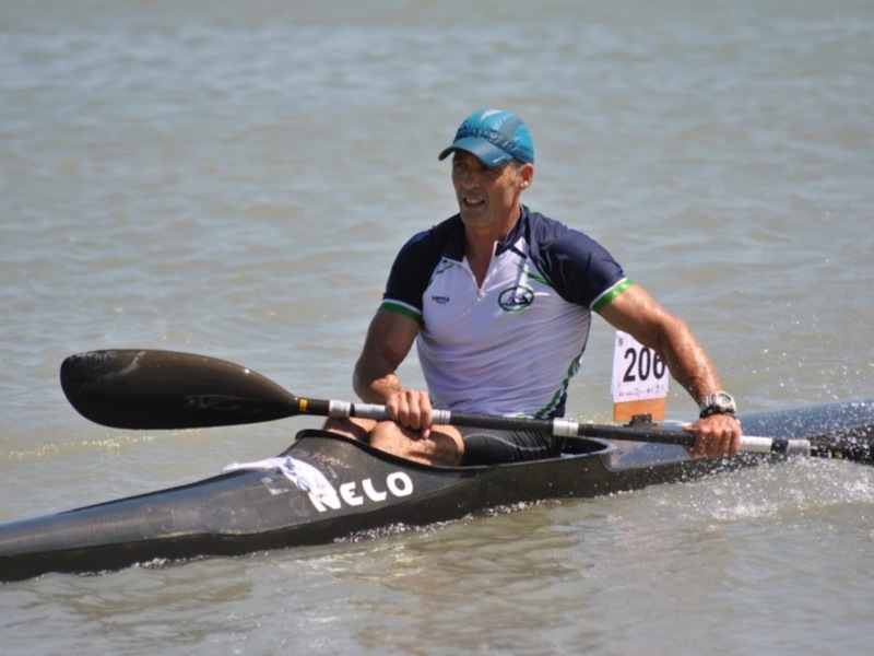 Un competidor de kayak en acción, con una camiseta blanca y azul y un número 206 en el fondo.