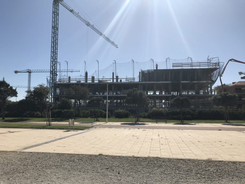 Construction site with cranes and a partially built building under a clear blue sky.