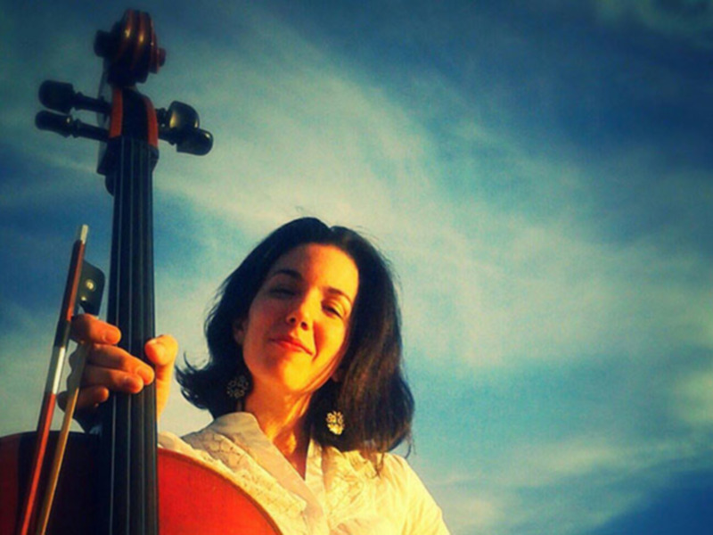Música bajo el cielo: una mujer con violonchelo sonríe con calma.