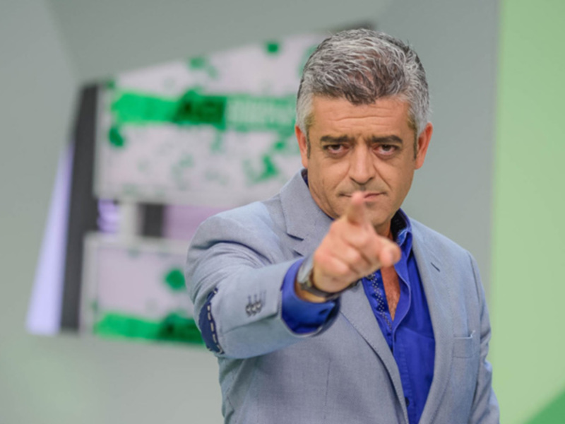 George Clooney en una escena de la serie "The Good Place", con un fondo verde y blanco.