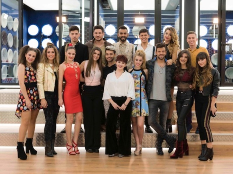 Grupo de personas posando en un estudio de televisión, vestidos de moda moderna y con un fondo de luces azules.
