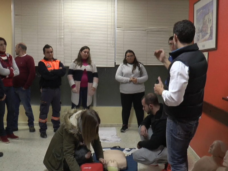 Un grupo de personas aprendiendo sobre primeros auxilios en una sala de conferencias.