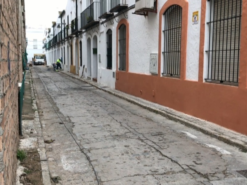 Calle estrecha con edificios blancos y paredes de ladrillo rojo, con una bicicleta aparcada en el borde de la calle.