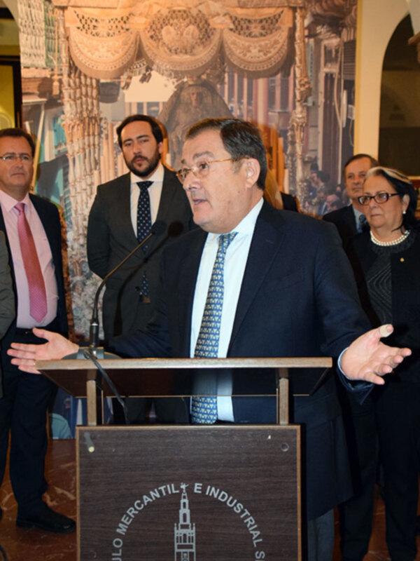 El presidente del Círculo Mercantil de Sevilla, en un evento formal con una imagen histórica al fondo.