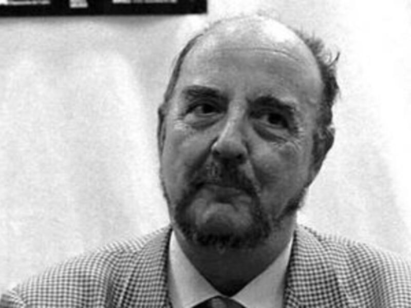 Retrato en blanco y negro de un hombre con barba y bigote, vistiendo traje y corbata.