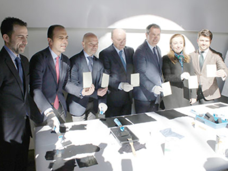 Una imagen de una reunión formal con varios hombres y mujeres en trajes, sosteniendo documentos. La escena se centra en una mesa con varios papeles y un marcador azul. La iluminación es suave, destacando la concentración de los participantes en el documento que sostienen.