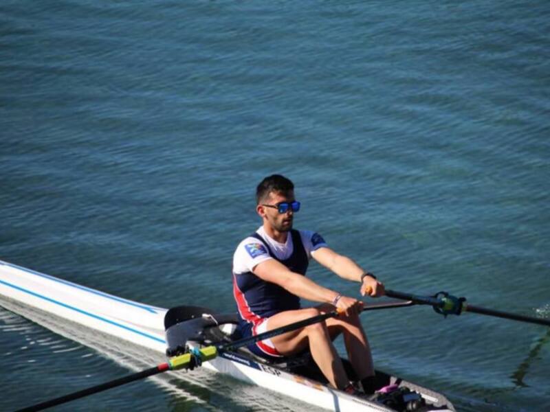 Atleta en acción durante una competición de remo en un lago tranquilo.