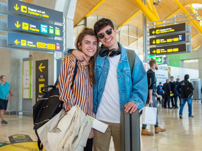 Amor en el aeropuerto: una pareja sonríe mientras se preparan para su viaje.