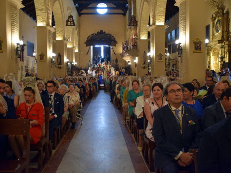 Una imagen de una iglesia con arcos y vitrales, donde una multitud de personas vestidas formalmente se reúne en el coro. La iluminación es suave y dorada, creando un ambiente sereno y reverente.