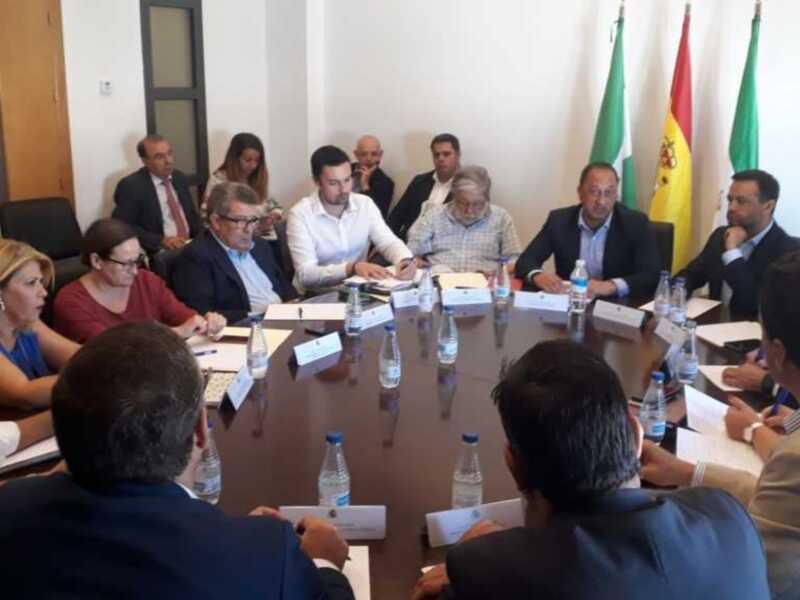 Reunión de trabajo en una sala de conferencias con banderas y documentos en la mesa.