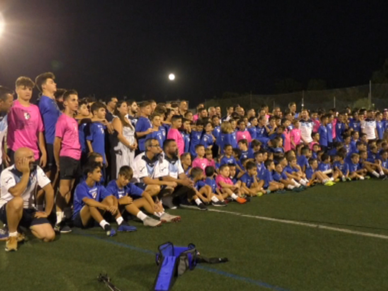 Equipo de fútbol posando en el campo de noche.