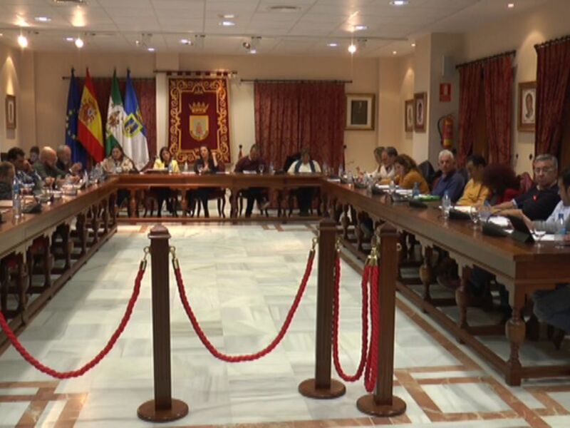 Sala de reuniones con una mesa grande, banderas en el fondo y cortinas rojas.