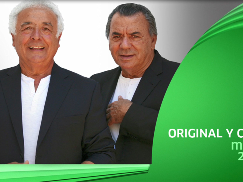 Dos hombres sonrientes posan juntos, uno con una camisa blanca y el otro con un chaleco negro. La imagen está acompañada por una bandera verde y texto informativo sobre la emisión del programa.