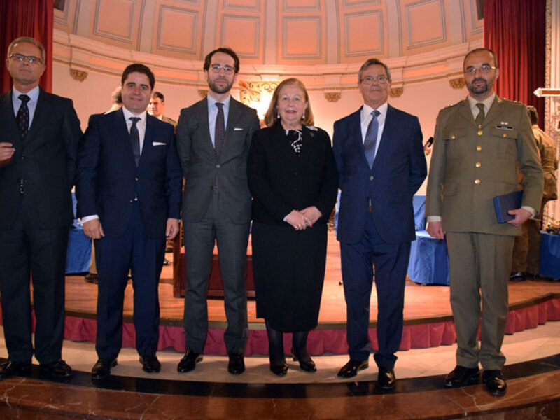 Una foto de grupo de personas en un evento formal, posando con elegancia en un escenario con decoración sofisticada.