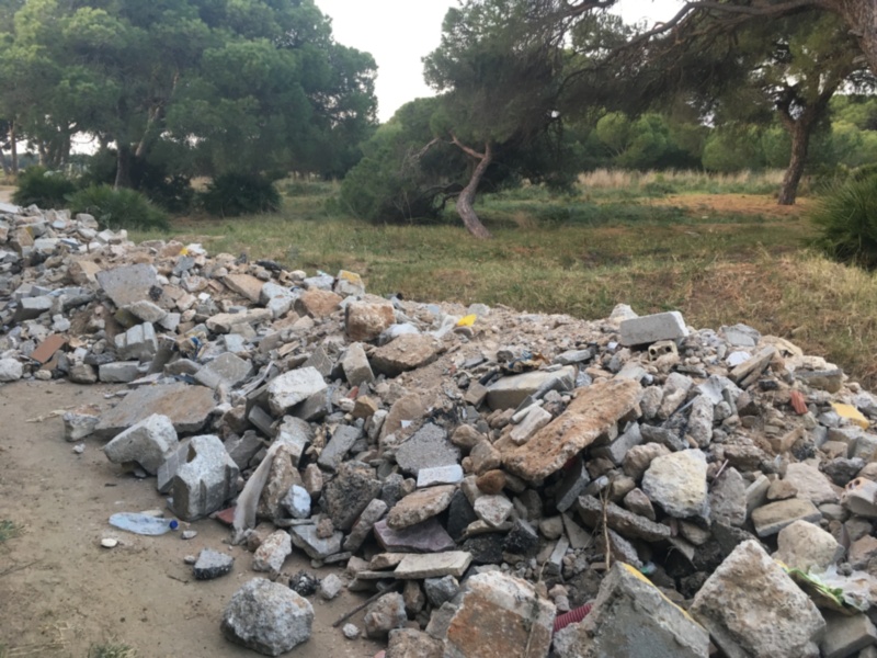 Pile of construction debris and trash in a natural setting.