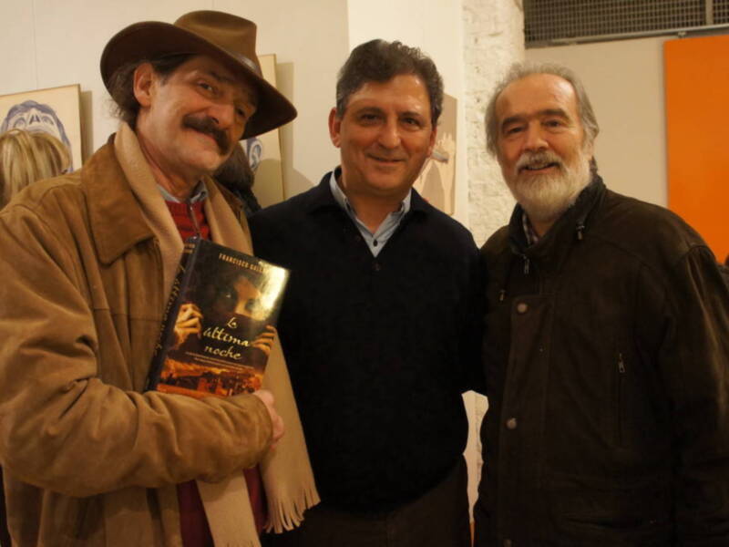 Tres personas sonrientes, una de ellas sostiene un libro titulado 'La última noche'.