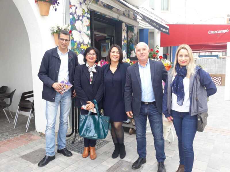 Grupo de personas en una calle con tienda de flores en el fondo