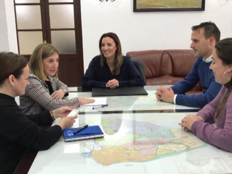 Reunión de trabajo en una oficina, personas discutiendo sobre un mapa y documentos.