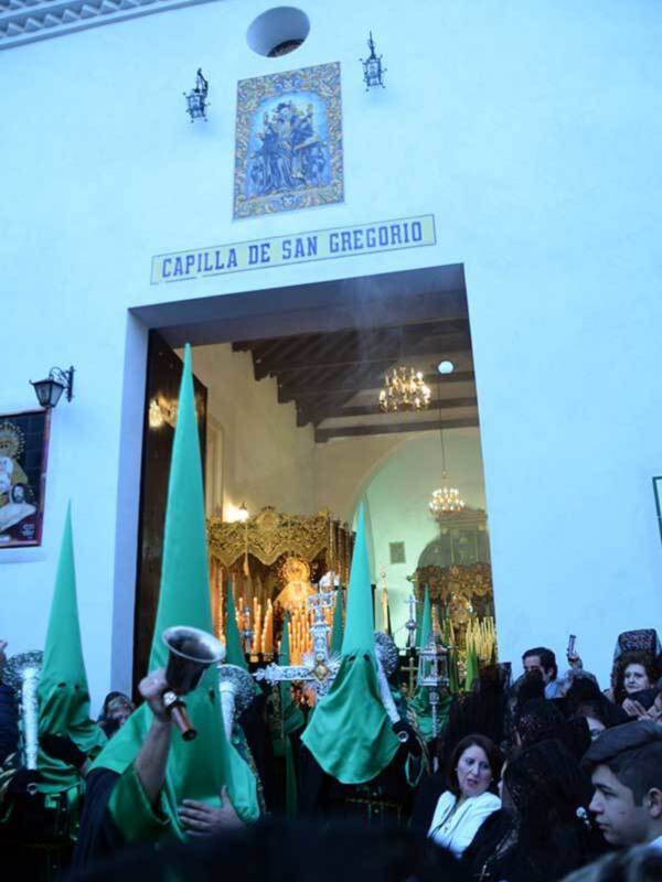 Procesión de Semana Santa en la Capilla de San Gregorio, con nazarenos en túnicas verdes y capas negras.